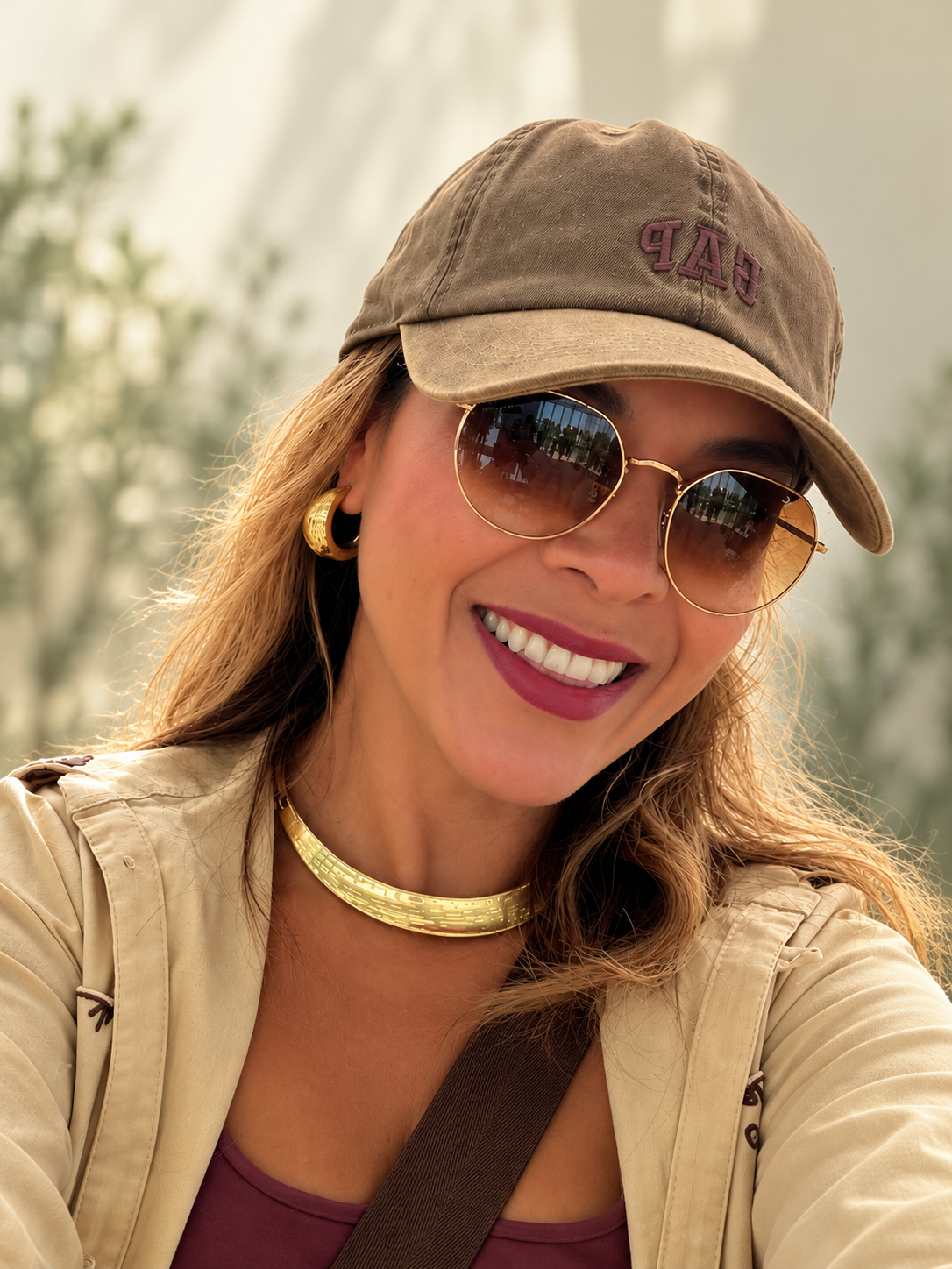 Camila Martins sorrindo, com boné e óculos de sol